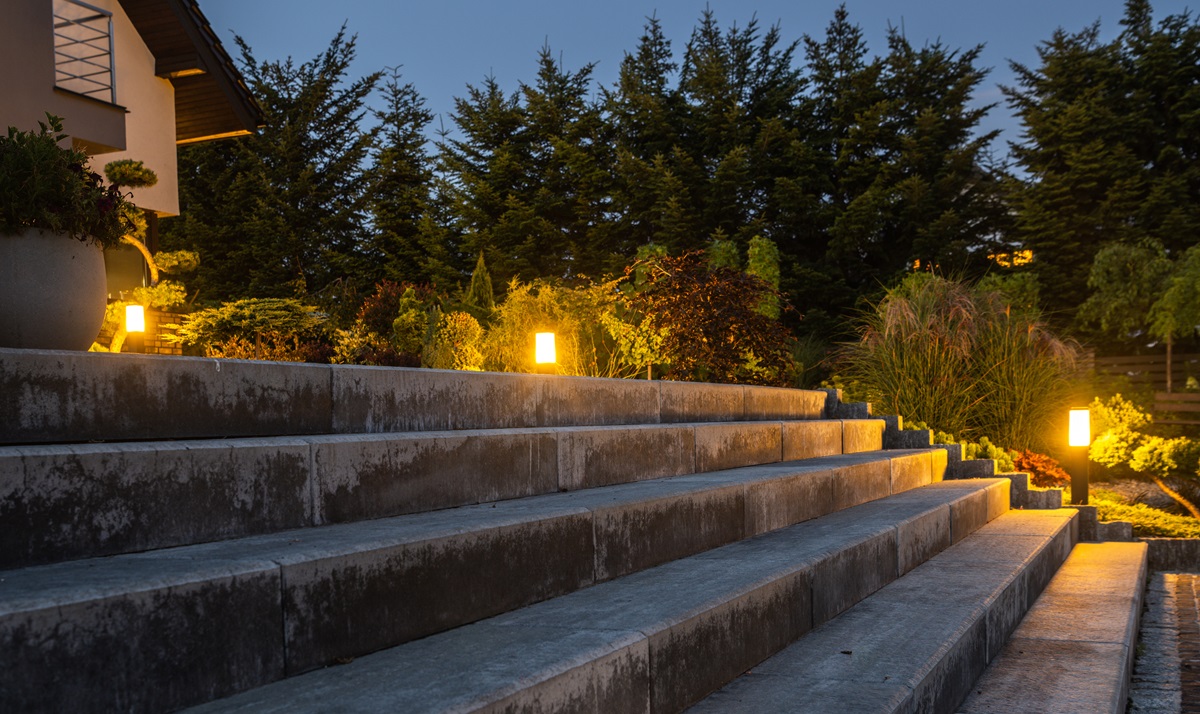 Wide stone garden steps lit by modern bollard lights beside planting beds