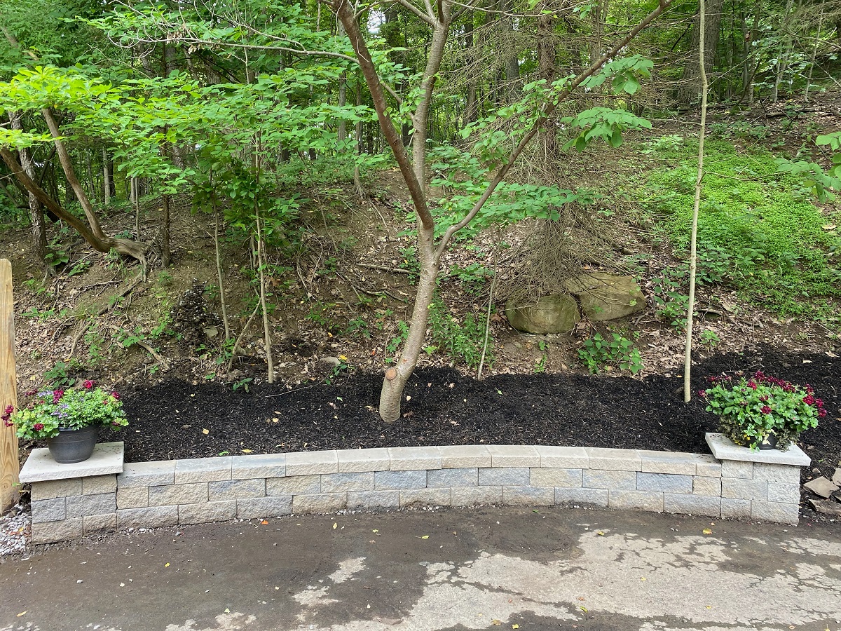 Curved block seat wall with planters holding back a fresh mulch bed by a driveway
