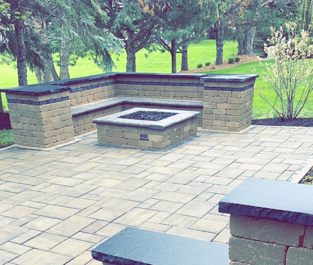 Paver patio with a square gas fire pit and an L shaped block seat wall with pillars