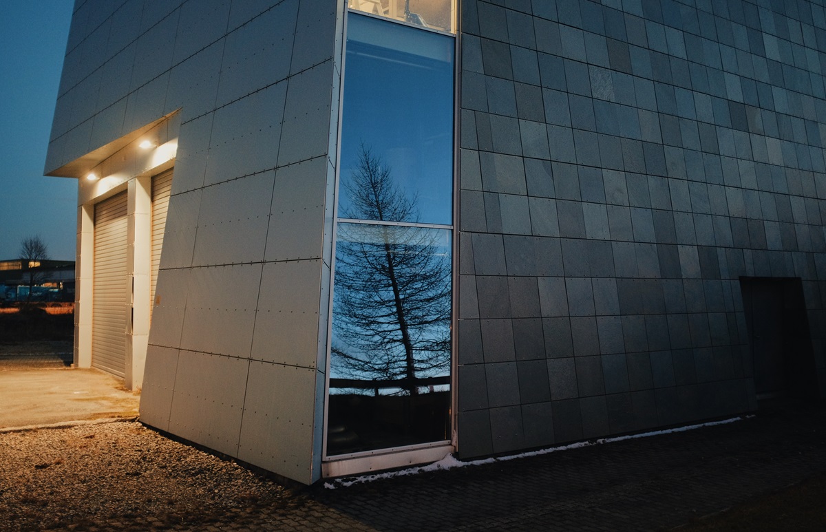 Exterior corner of a modern commercial building lit by wall-mounted floodlights