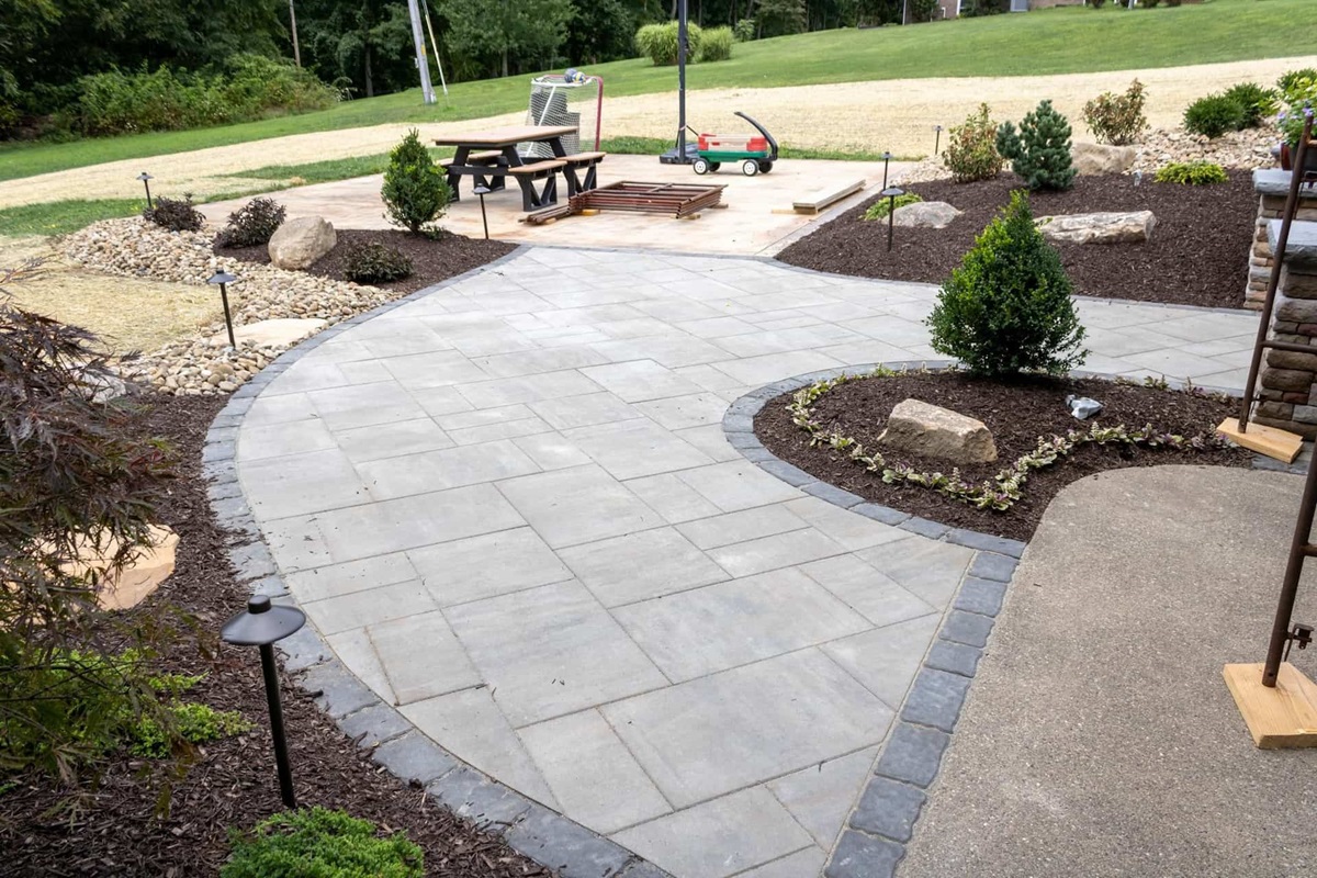How Mulching Helps Maintain a Healthy Lawn in Zelienople, PA 5 Curved paver patio and walkway edged with charcoal border stones and mulched planting beds