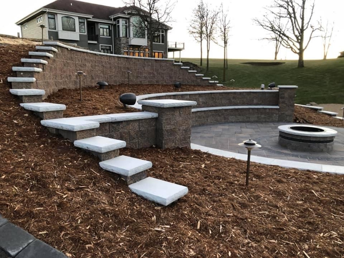 How Mulching Helps Maintain a Healthy Lawn in Zelienople, PA 1 Block retaining wall with cantilevered stone steps, fire pit patio and fresh mulch beds