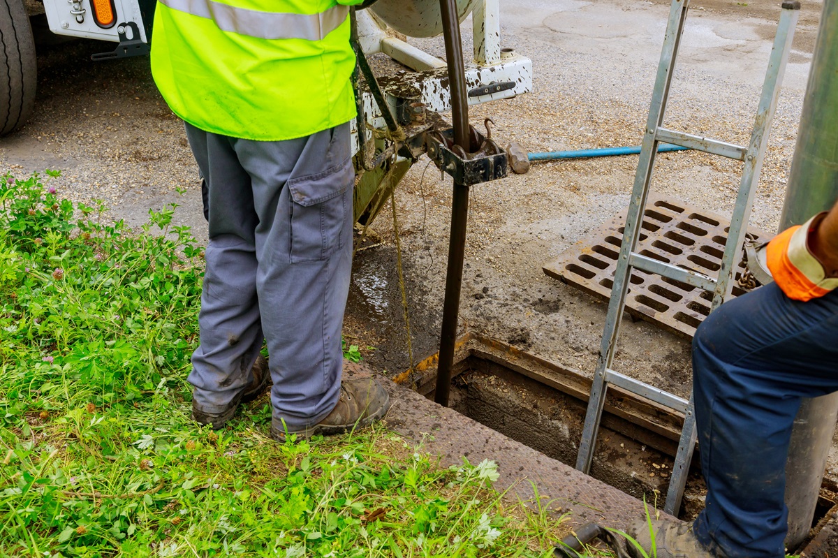 How Retaining Walls Can Improve Drainage and Prevent Erosion in Zelienople Landscapes 2 Utility crew in high visibility vests working over an open storm drain catch basin
