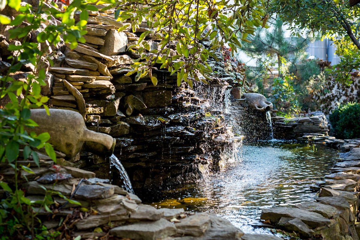 Stacked stone waterfall feature spilling into a garden pond