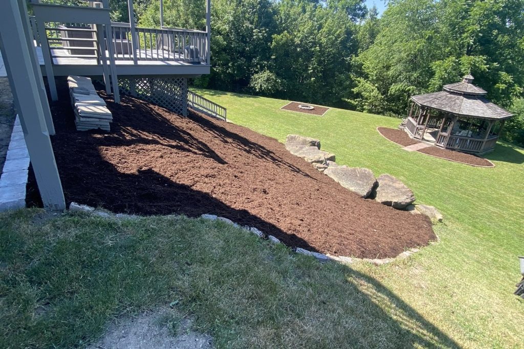 Freshly laid mulch bed with a cut stone edge beside a maintained green lawn in Greater Pittsburgh, PA