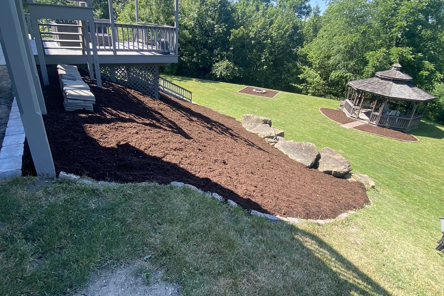 Mulch or Stone for Your Landscape Beds? 1 Freshly laid mulch bed with a cut stone edge beside a maintained green lawn in Greater Pittsburgh, PA