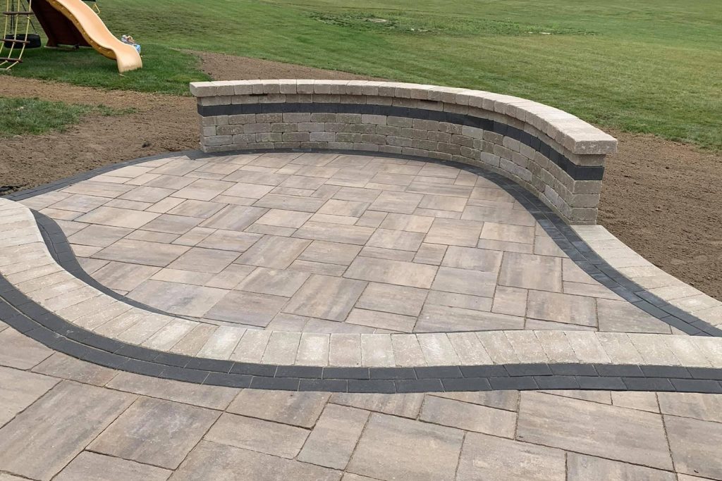 Paver patio with a curved seat wall and a mown lawn, built by Daily Landscaping in Western Pennsylvania