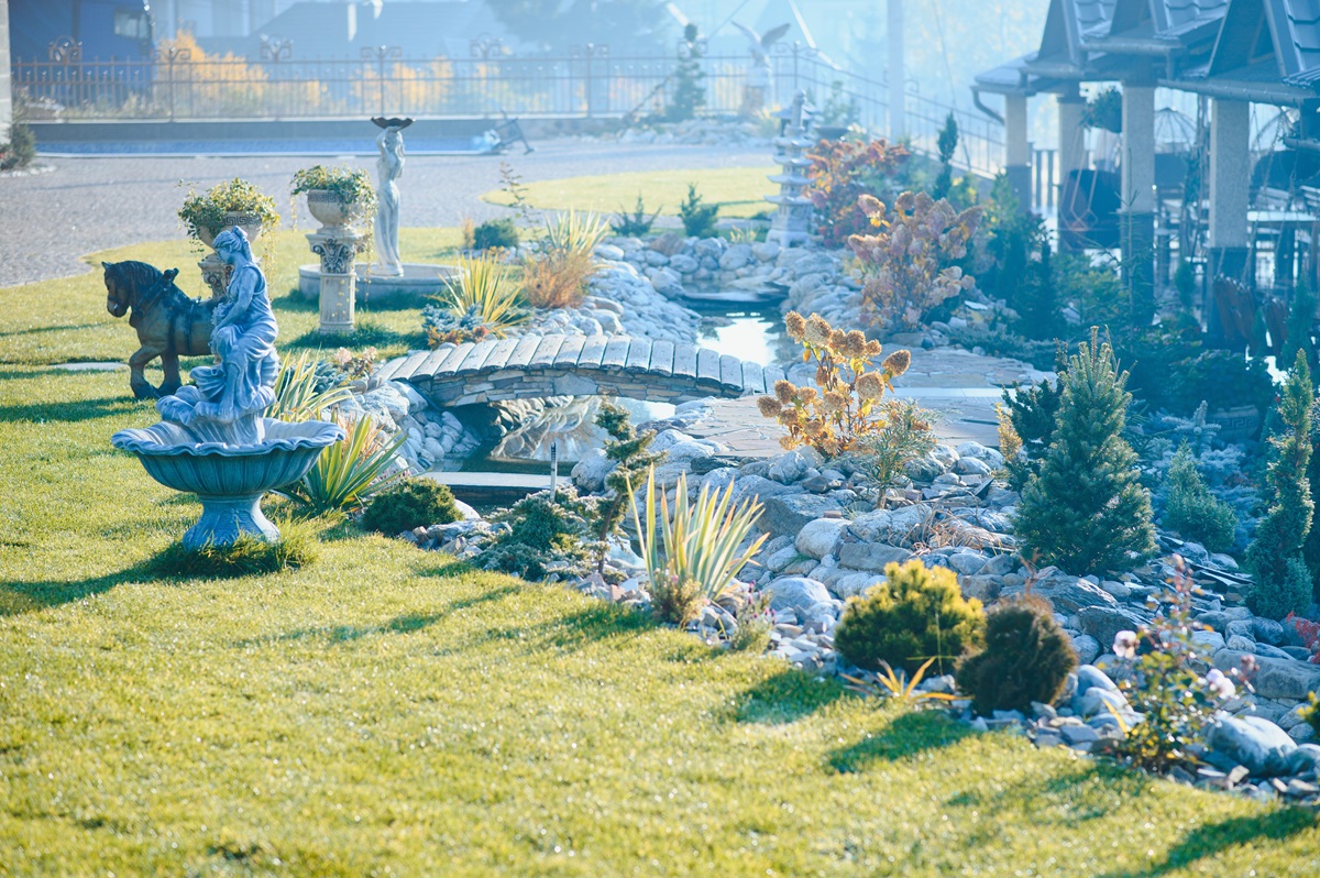 Frosty morning garden with a cherub fountain, small stone bridge and conifers