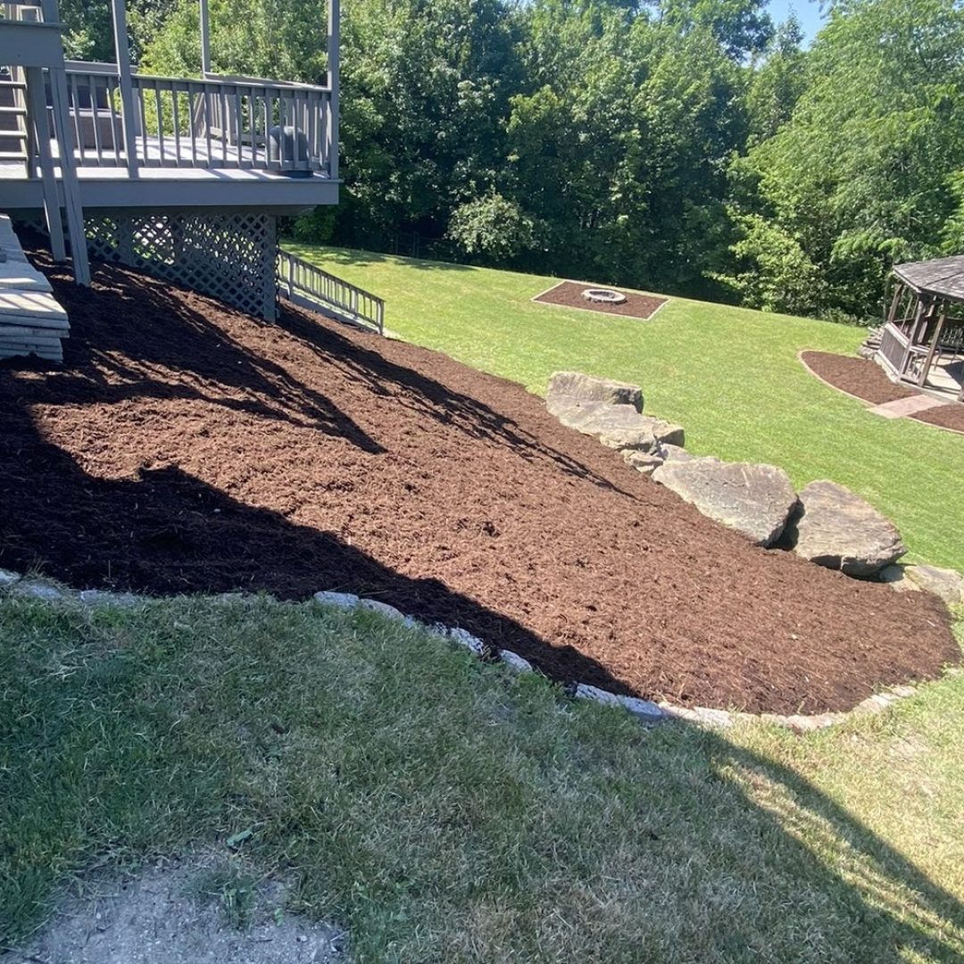 Freshly laid mulch bed with a cut stone edge beside a maintained green lawn in Greater Pittsburgh, PA